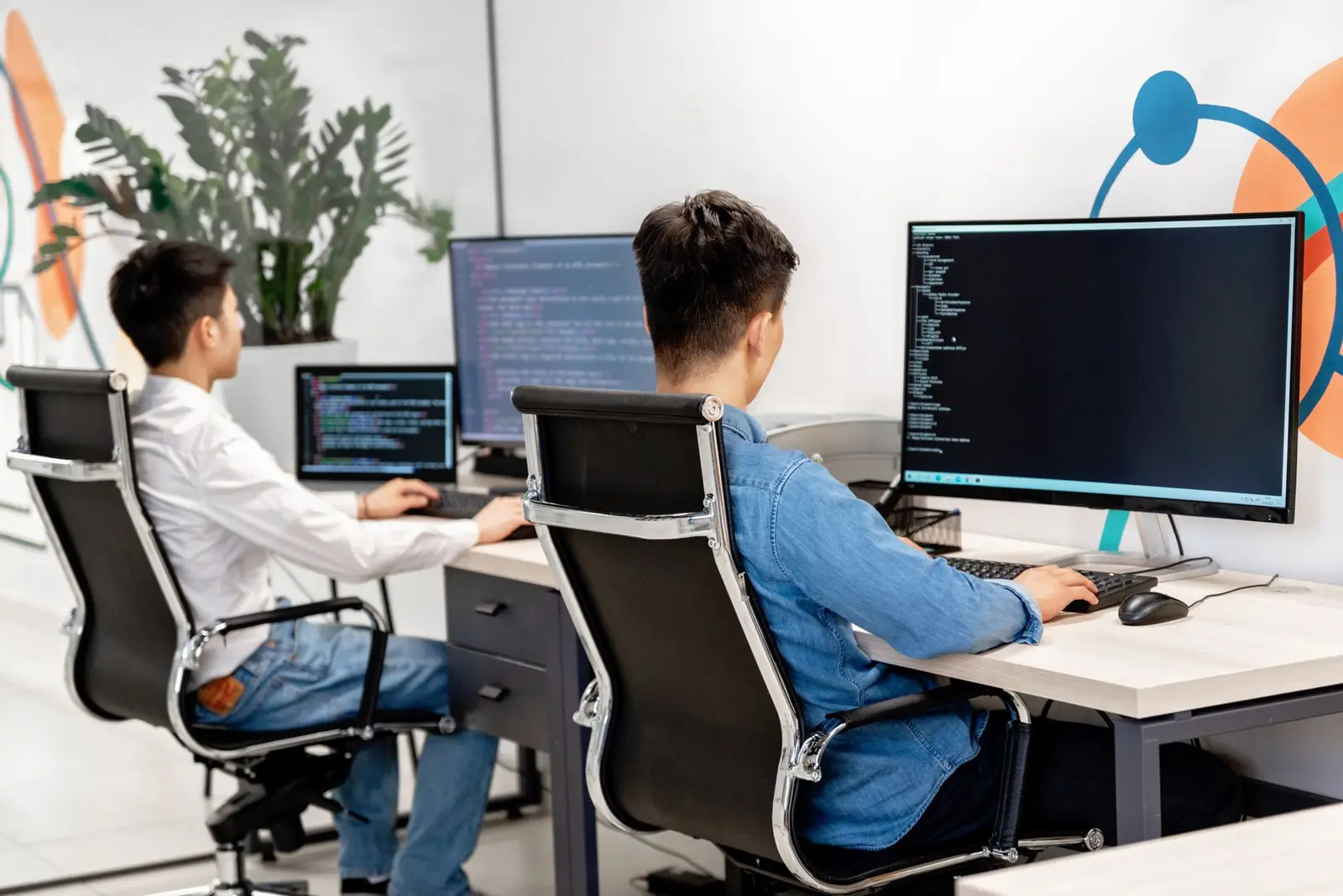 Two developers working at monitors in a modern office.